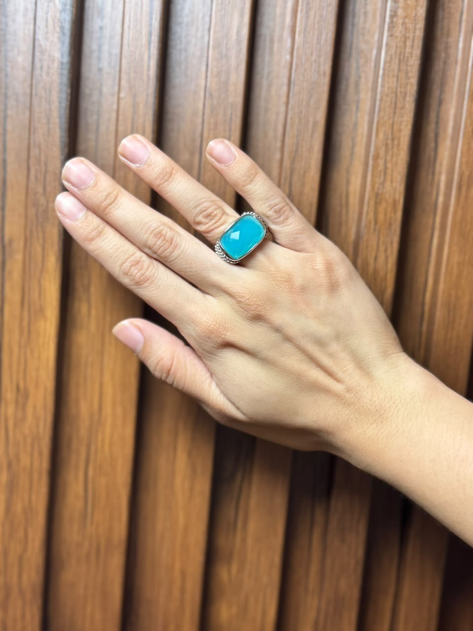 Anillo con cristal facetado turquesa y detalles entrelazados